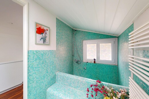 salle de bains avec plafond voûté, radiateur, lumière naturelle, mur en carrelage, et sol en finition bois