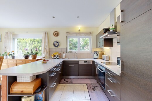 kitchen featuring light countertops, a peninsula, stainless steel oven, and backsplash
