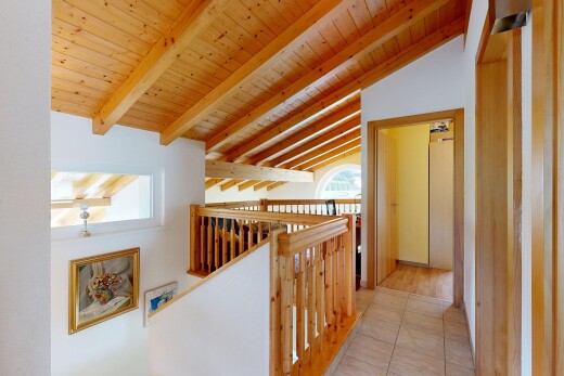 corridor with an upstairs landing and a wooden ceiling with exposed beams