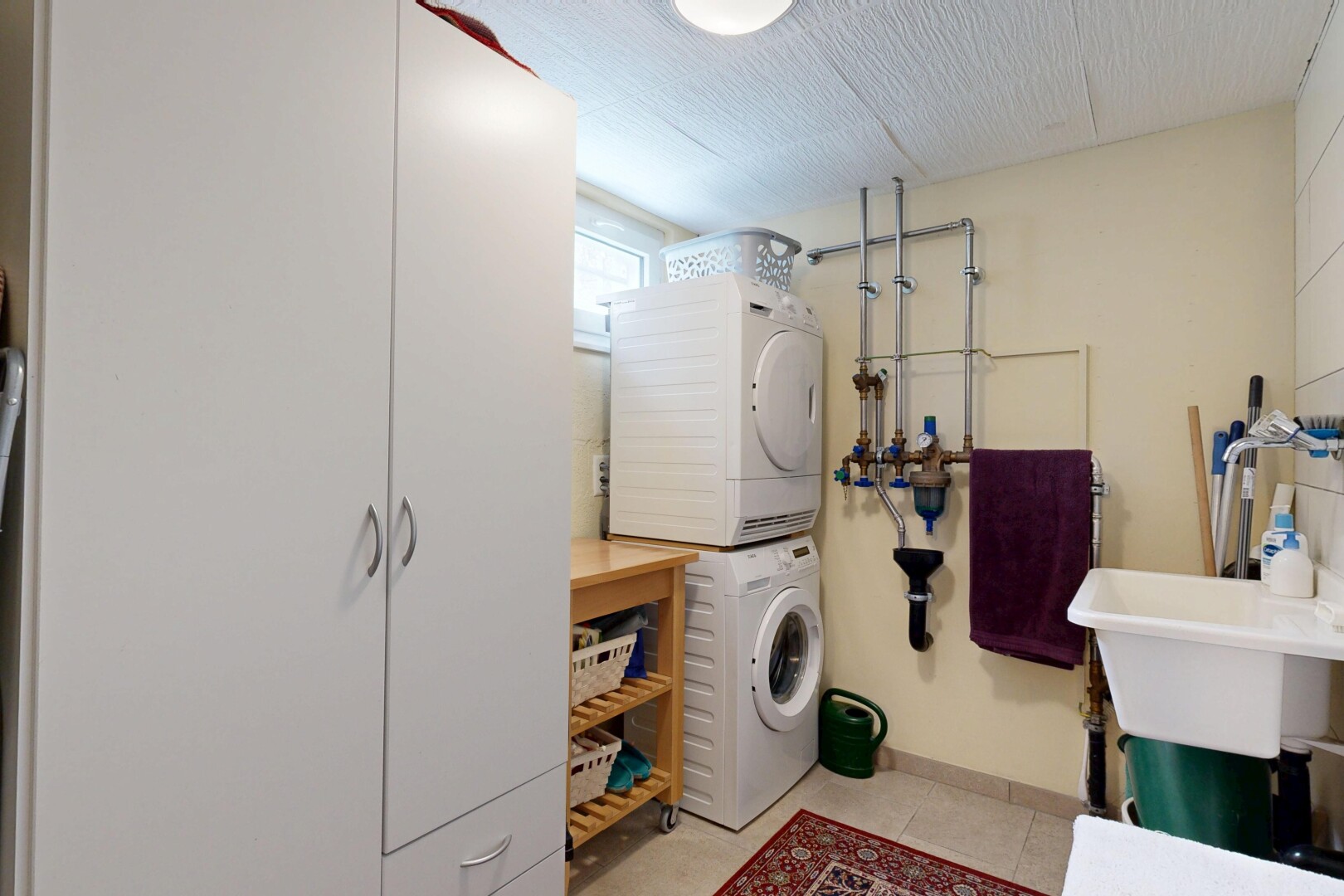 buanderie avec light floor, buanderie, inside property, lave-linge et sèche-linge superposés, et cloison sèche