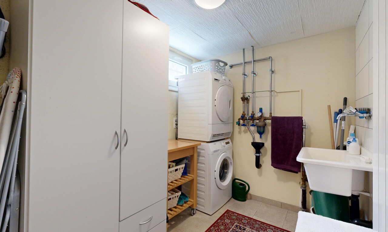 buanderie avec light floor, buanderie, inside property, lave-linge et sèche-linge superposés, et cloison sèche