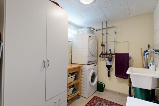 buanderie avec light floor, buanderie, inside property, lave-linge et sèche-linge superposés, et cloison sèche