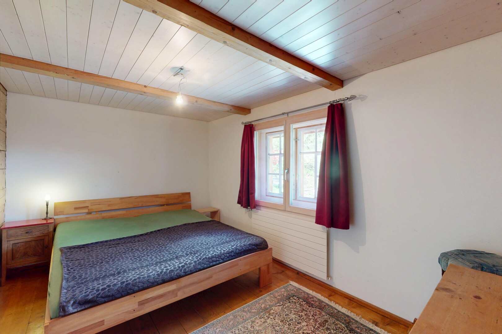chambre avec cloison sèche, plafond à poutres, sol en finition bois, et lumière naturelle