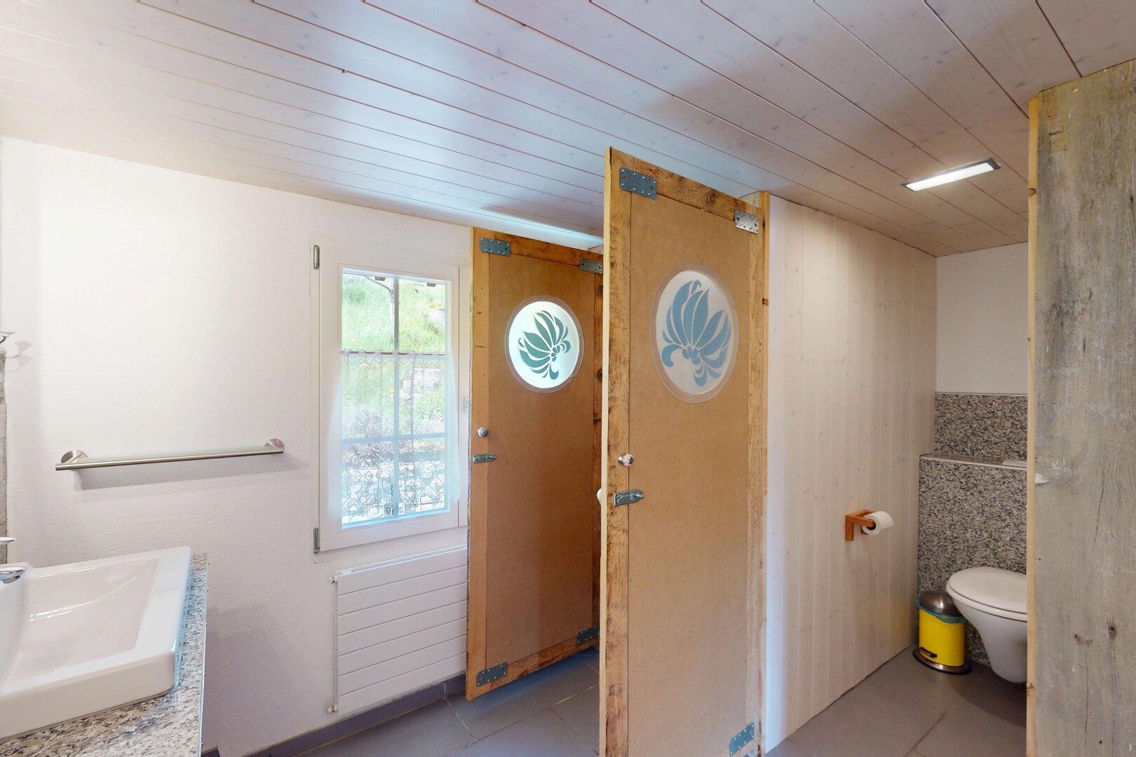salle de bains avec plafond en bois, évier, radiateur, toilette, et lumière naturelle