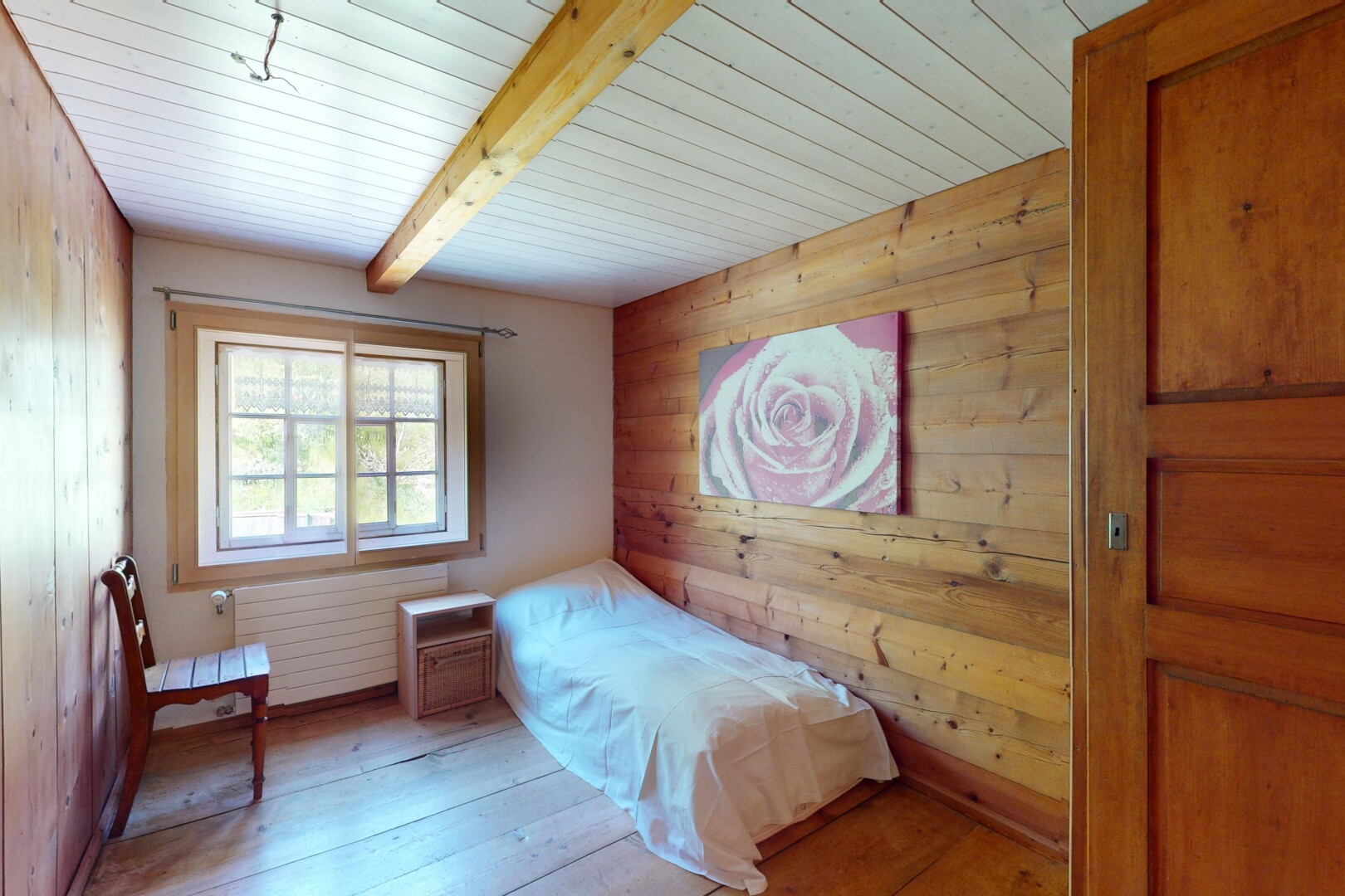chambre avec mur en bois, sol en finition bois, lumière naturelle, et radiateur