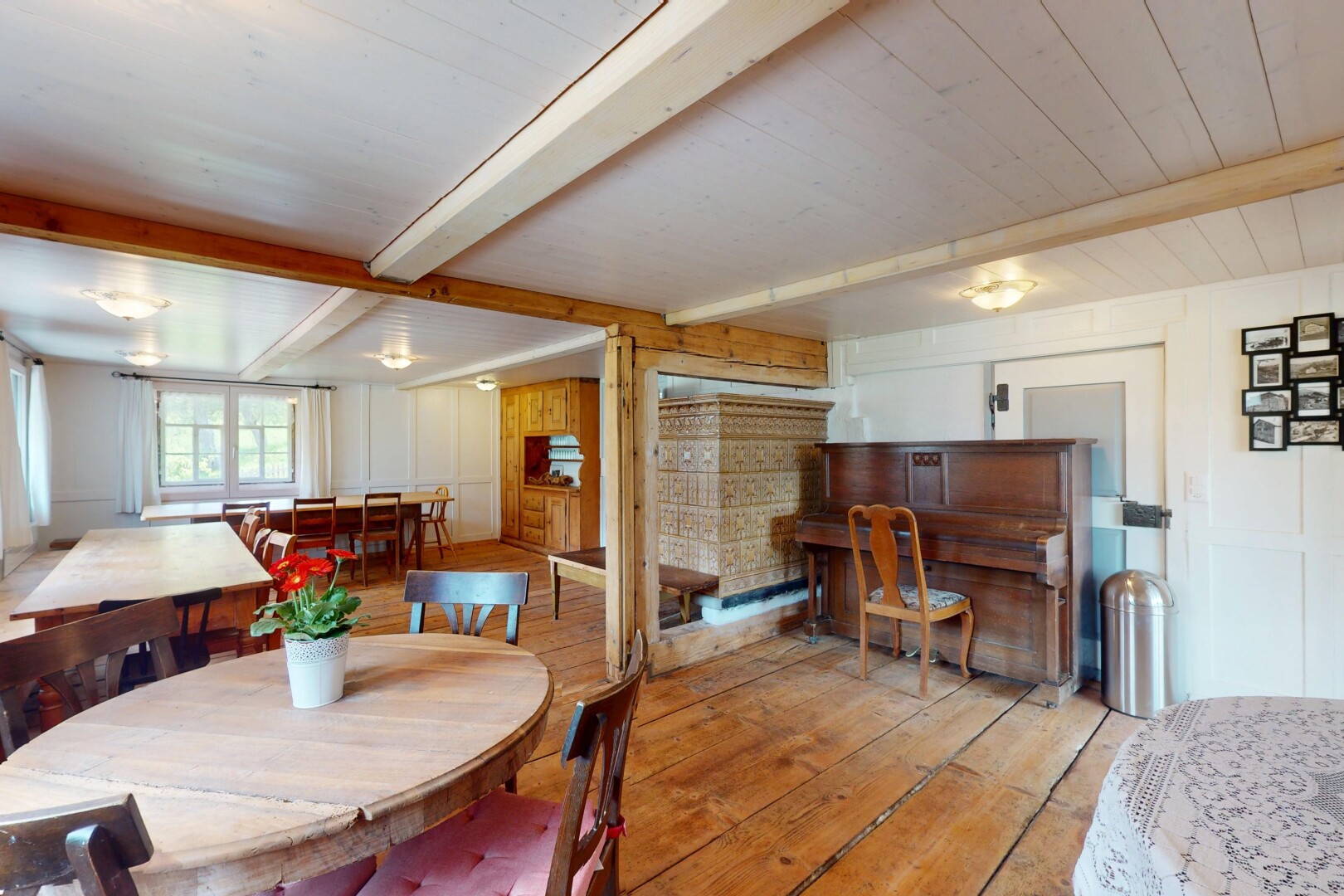 salle à manger avec plafond à poutres, lumière naturelle, et sol en finition bois