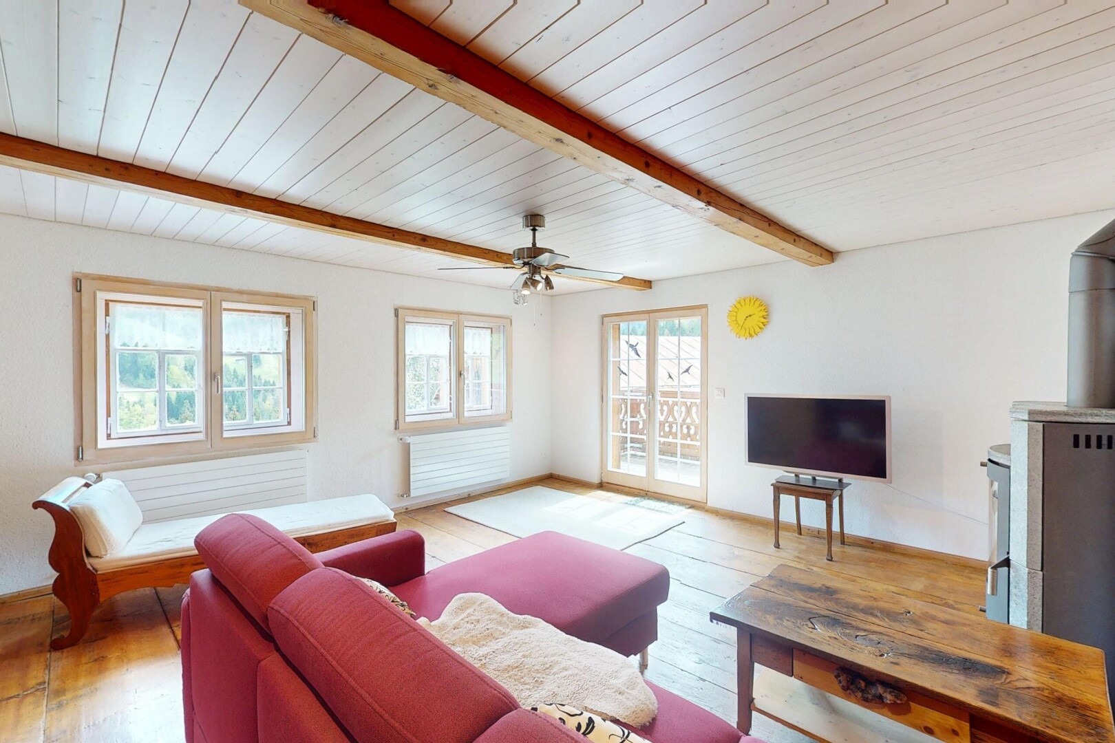 salon avec lumière naturelle, plafond à poutres, télévision, sol en finition bois, et cloison sèche
