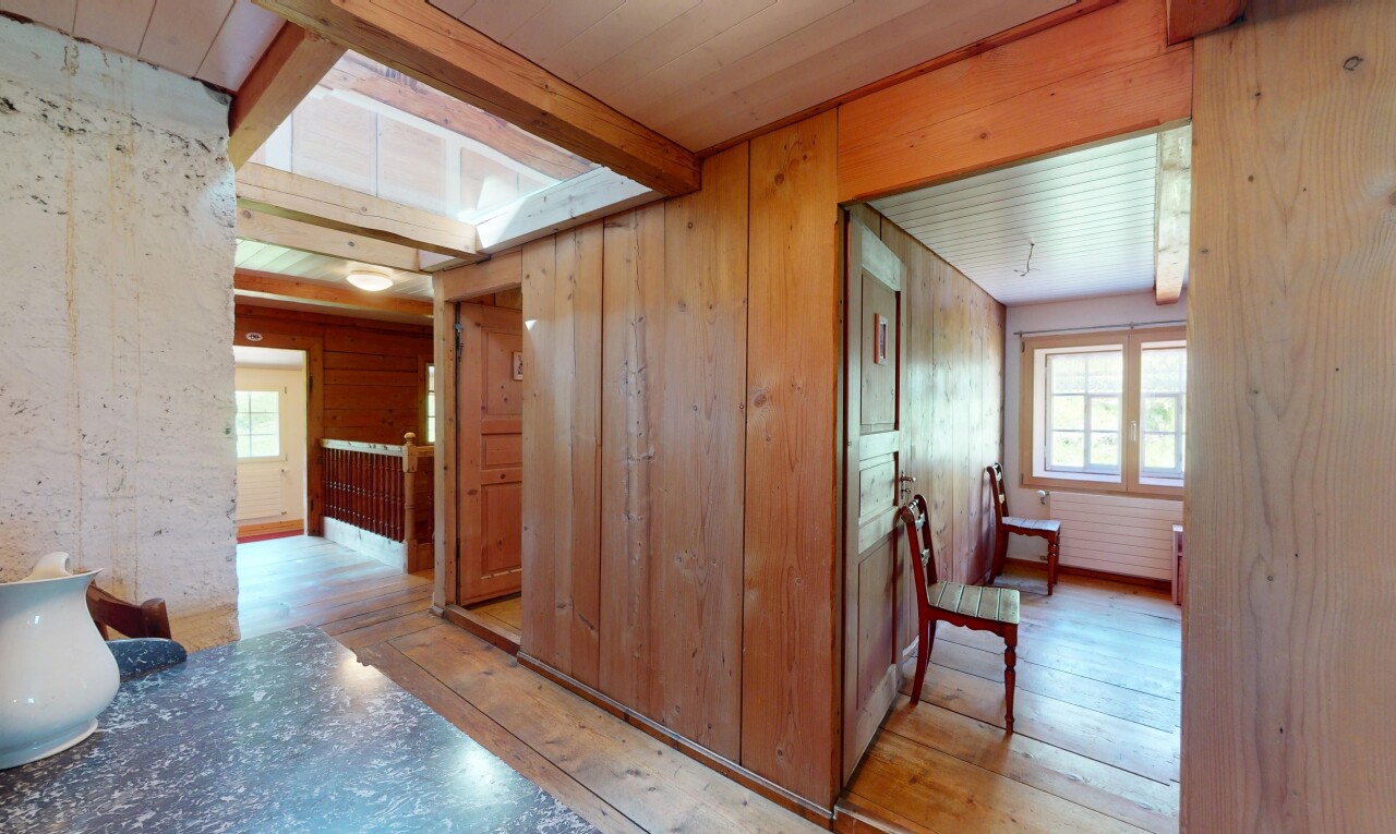 couloir avec plafond à poutres, lumière naturelle, et sol en finition bois