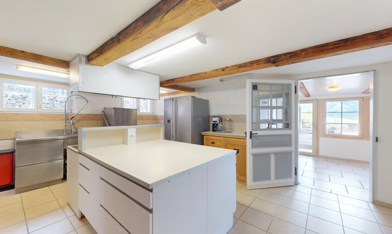 cuisine avec lumière naturelle, réfrigérateur, sol en carrelage, et plafond à poutres
