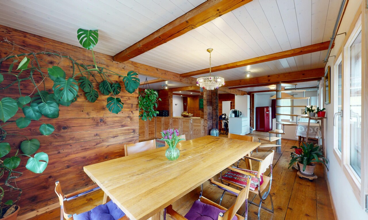 salle à manger avec lumière naturelle, plafond en bois, lustre remarquable, plafond à poutres, et sol en finition bois