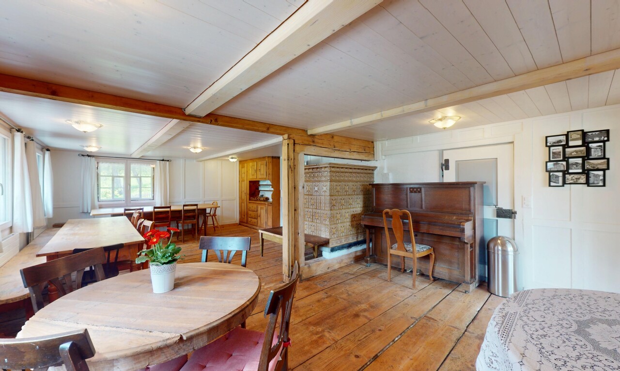 salle à manger avec plafond à poutres, lumière naturelle, et sol en finition bois