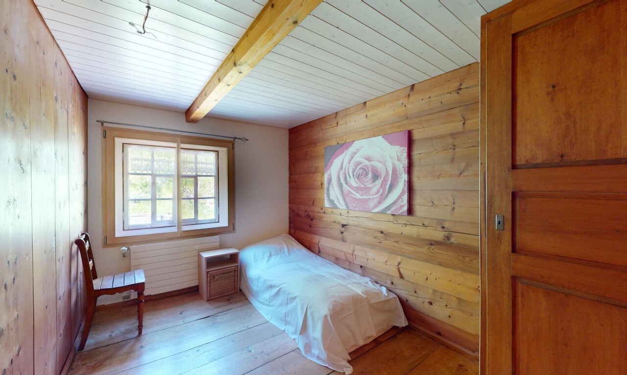 chambre avec mur en bois, sol en finition bois, lumière naturelle, et radiateur