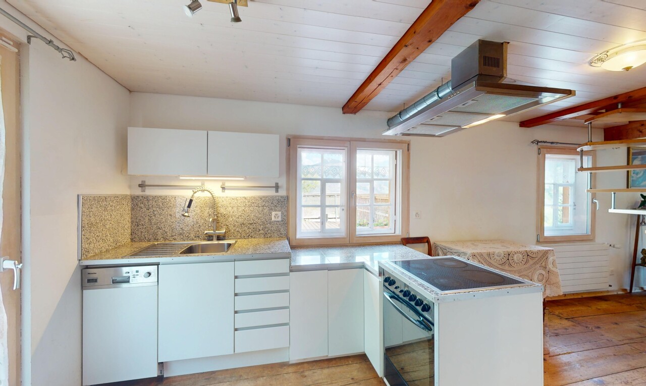 cuisine avec lave-vaisselle, lumière naturelle, plans de travail, sol en finition bois, et dosseret