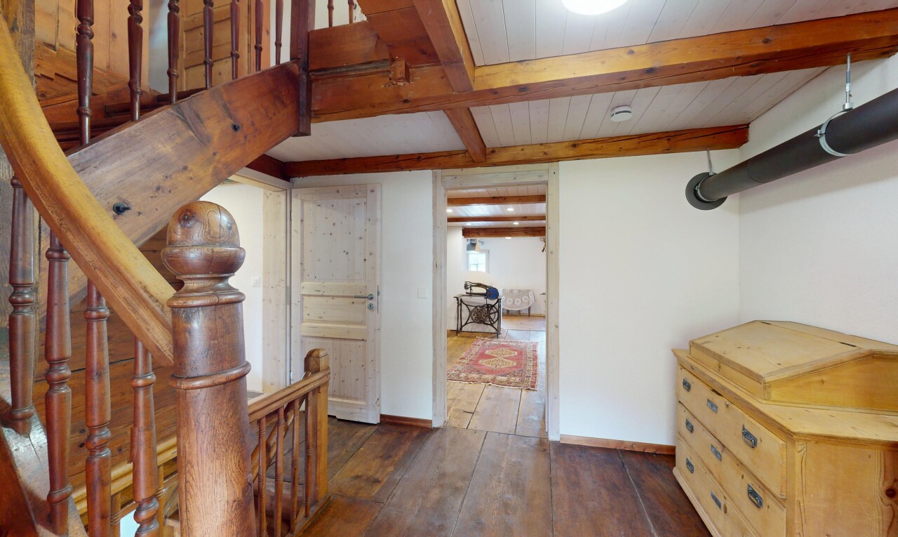 espace intérieur avec plinthes murales, sol en finition bois, plafond à poutres, cloison sèche, et lumière naturelle