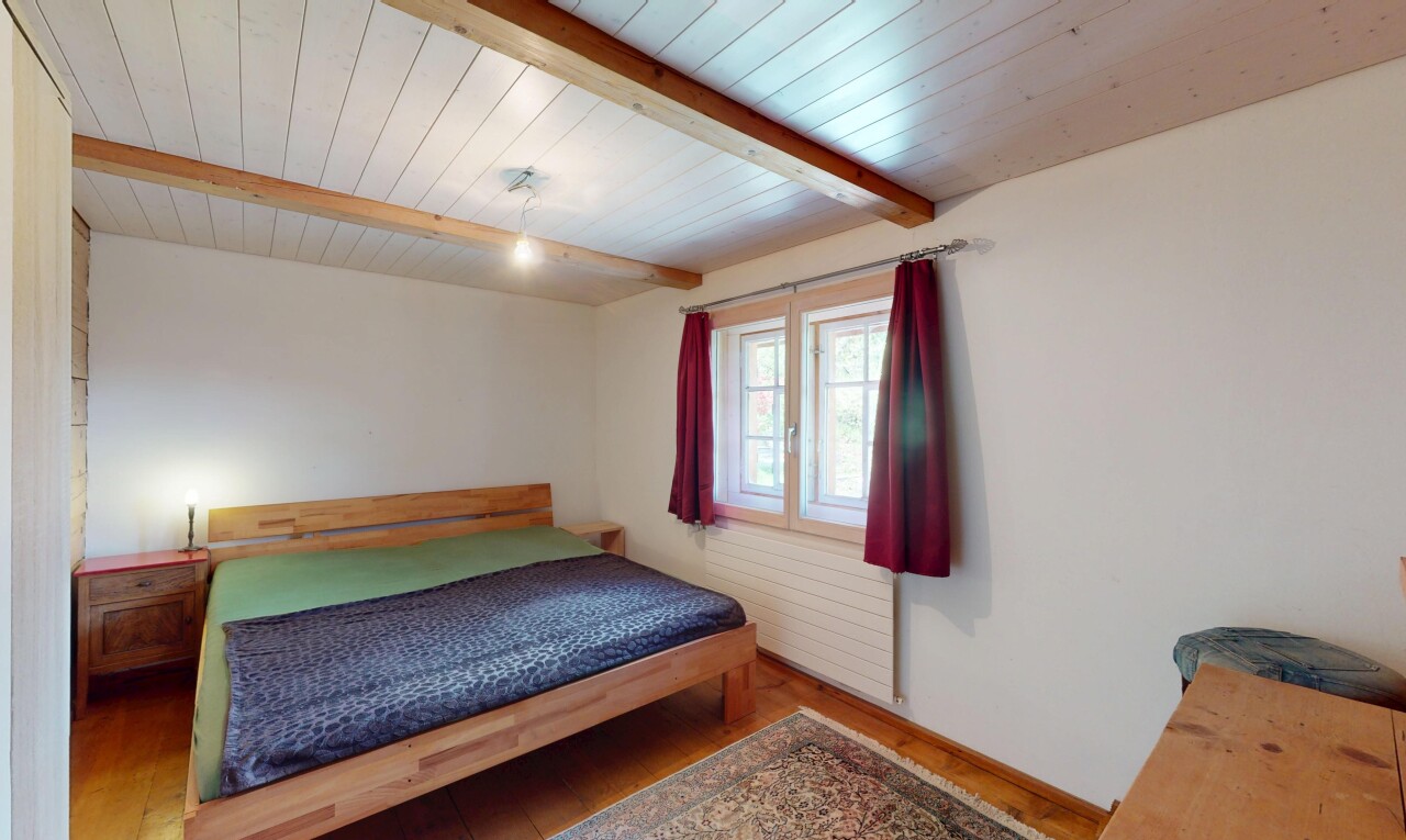 chambre avec cloison sèche, plafond à poutres, sol en finition bois, et lumière naturelle