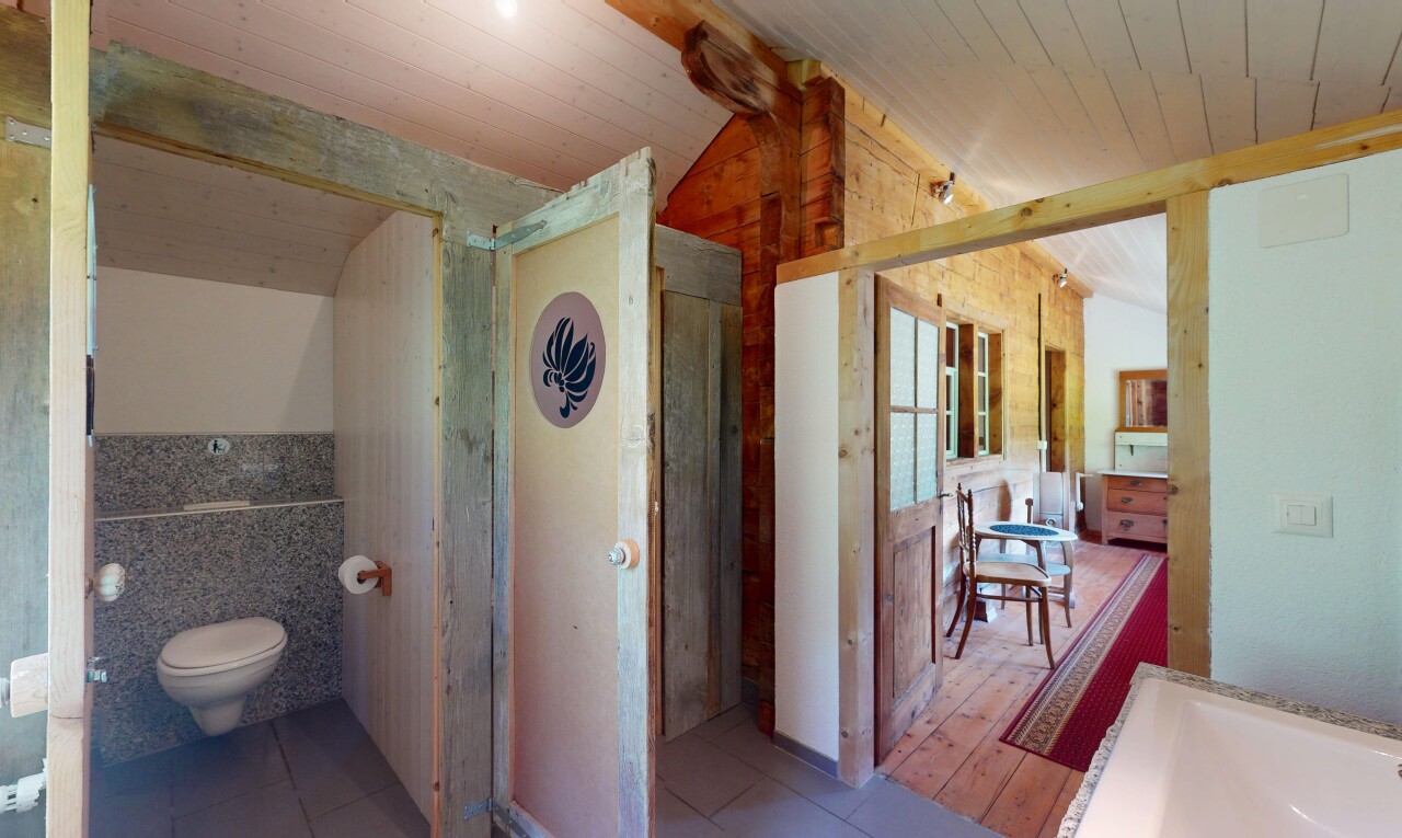 salle de bains avec plafond voûté, plafond en bois, sol en carrelage, et toilette