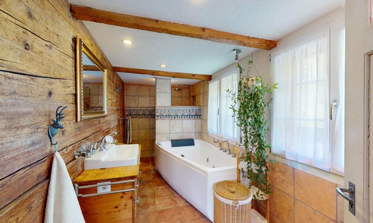 salle de bains avec évier, miroir, lumière naturelle, et plafond à poutres
