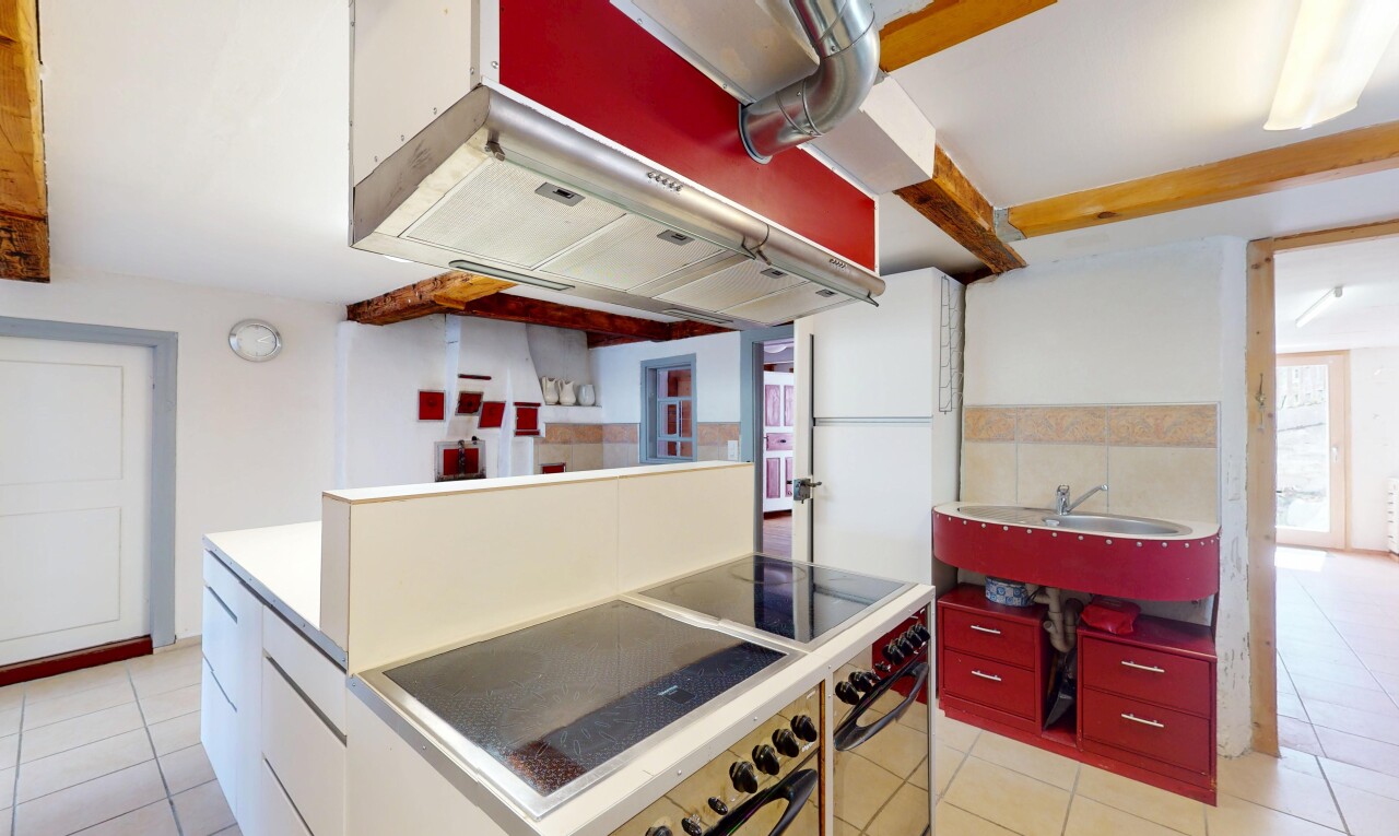 cuisine avec four, évier, lumière naturelle, sol en carrelage, et cloison sèche