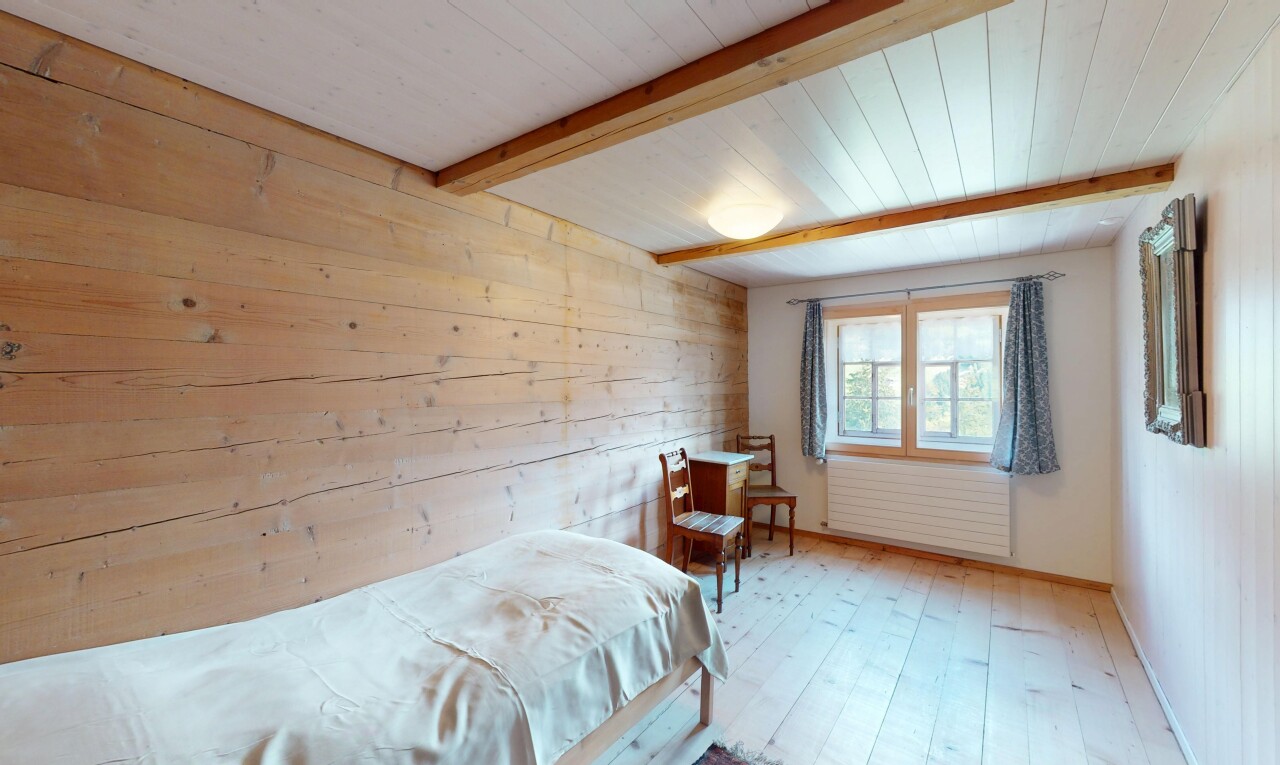 chambre avec lumière naturelle, plafond à poutres, mur en bois, et sol en finition bois