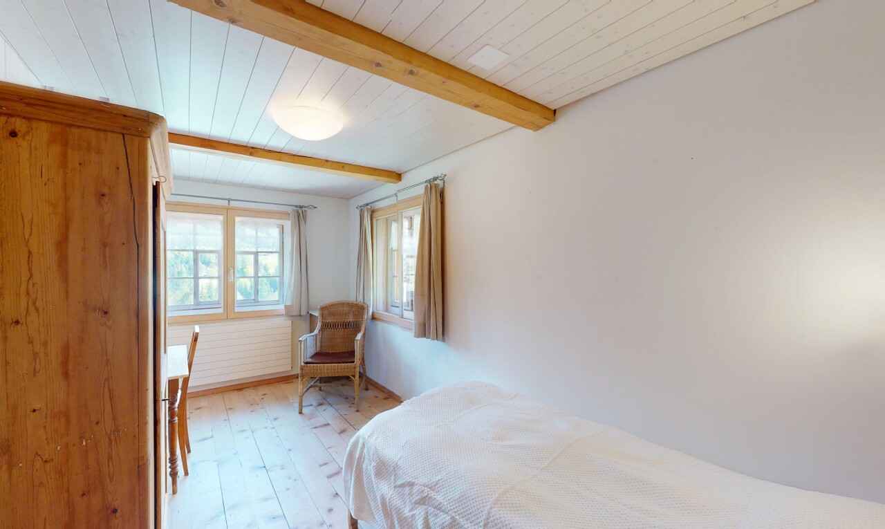 chambre avec sol en finition bois, lumière naturelle, plafond à poutres, et cloison sèche