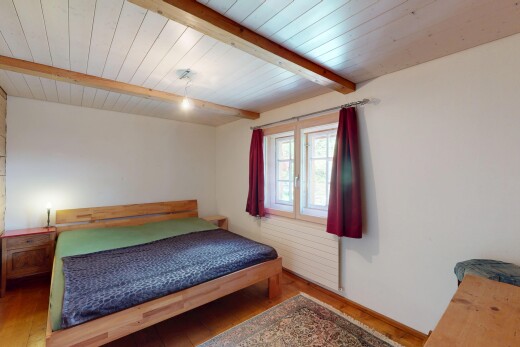 chambre avec cloison sèche, plafond à poutres, sol en finition bois, et lumière naturelle