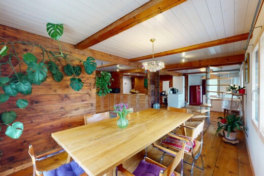 salle à manger avec lumière naturelle, plafond en bois, lustre remarquable, plafond à poutres, et sol en finition bois
