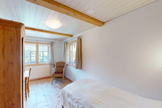 chambre avec sol en finition bois, lumière naturelle, plafond à poutres, et cloison sèche