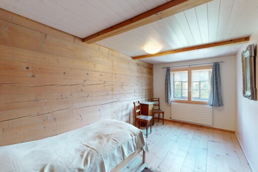chambre avec lumière naturelle, plafond à poutres, mur en bois, et sol en finition bois
