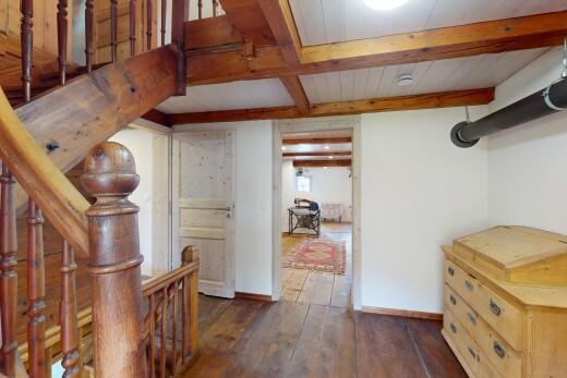 espace intérieur avec plinthes murales, sol en finition bois, plafond à poutres, cloison sèche, et lumière naturelle