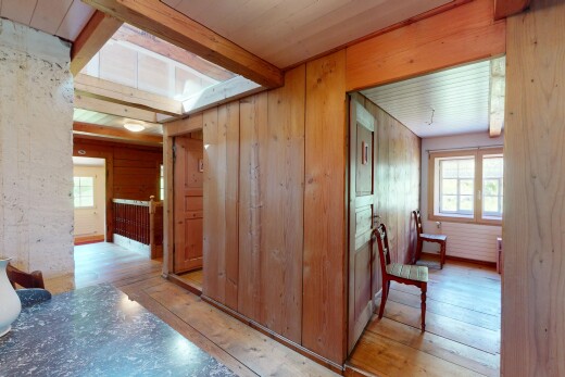 couloir avec plafond à poutres, lumière naturelle, et sol en finition bois