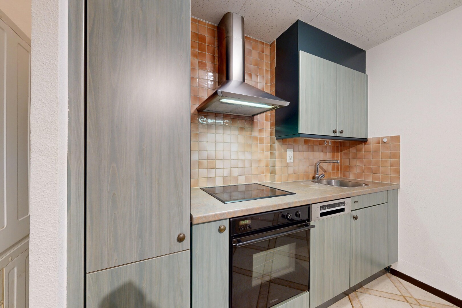 cuisine avec hotte, four, light floor, plans de travail, et light countertops