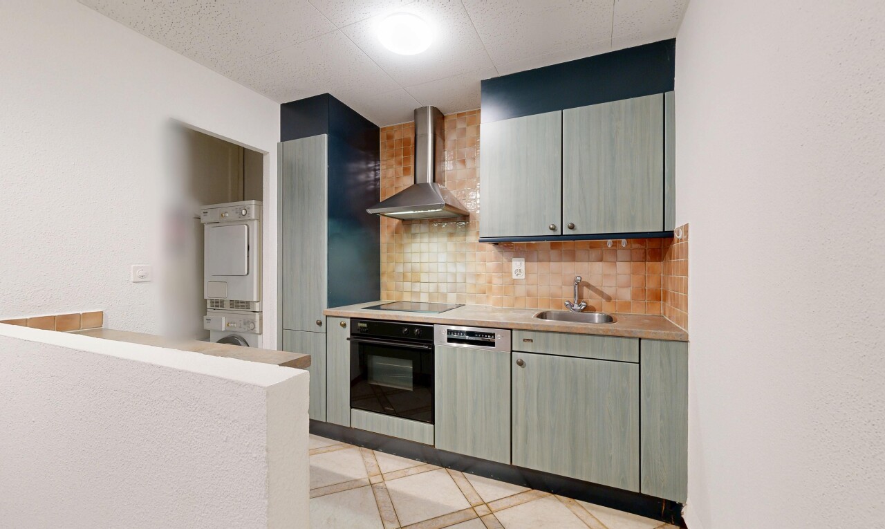 cuisine avec hotte, four, light floor, light countertops, et plans de travail