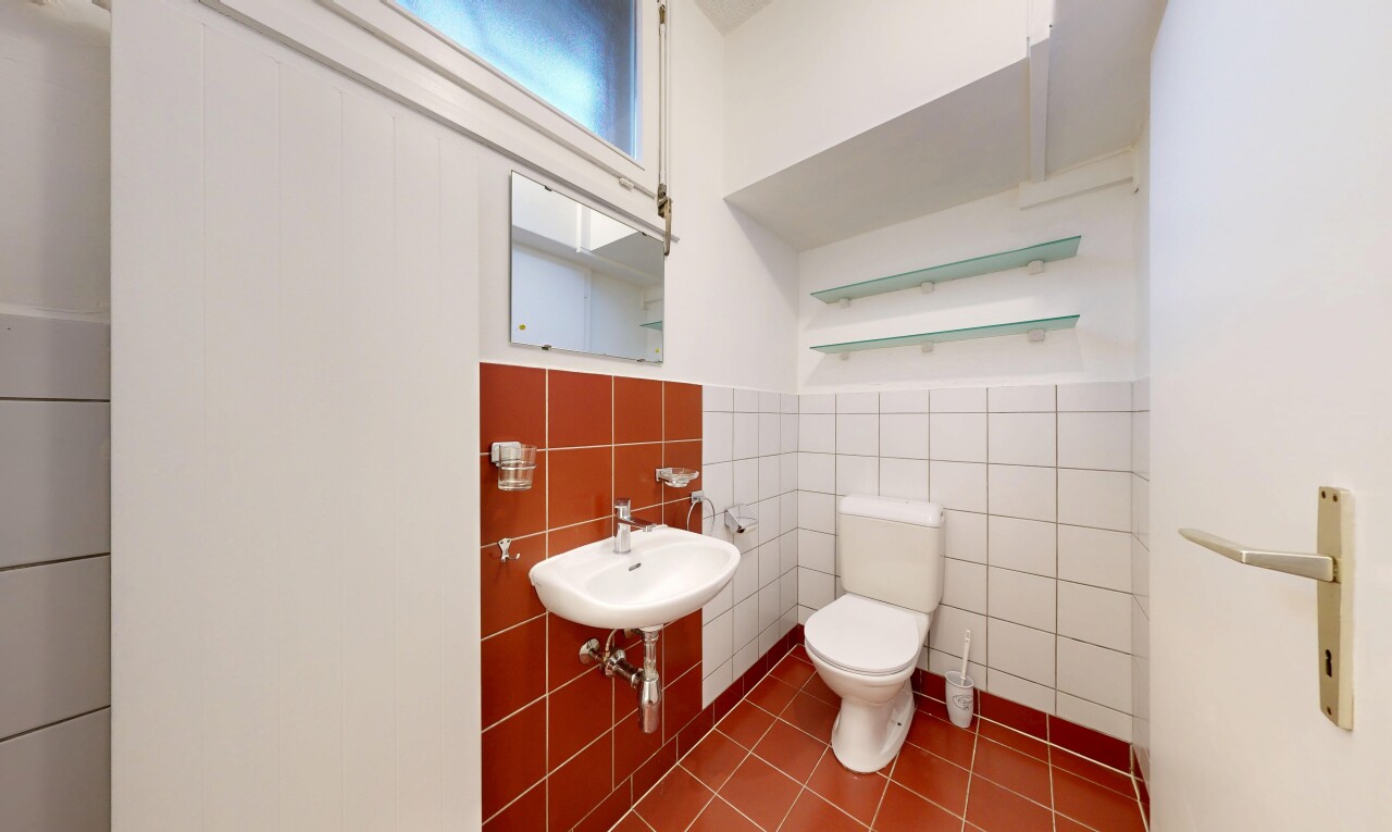 salle de bains avec toilette, inside community, miroir, tile wall, et drywall