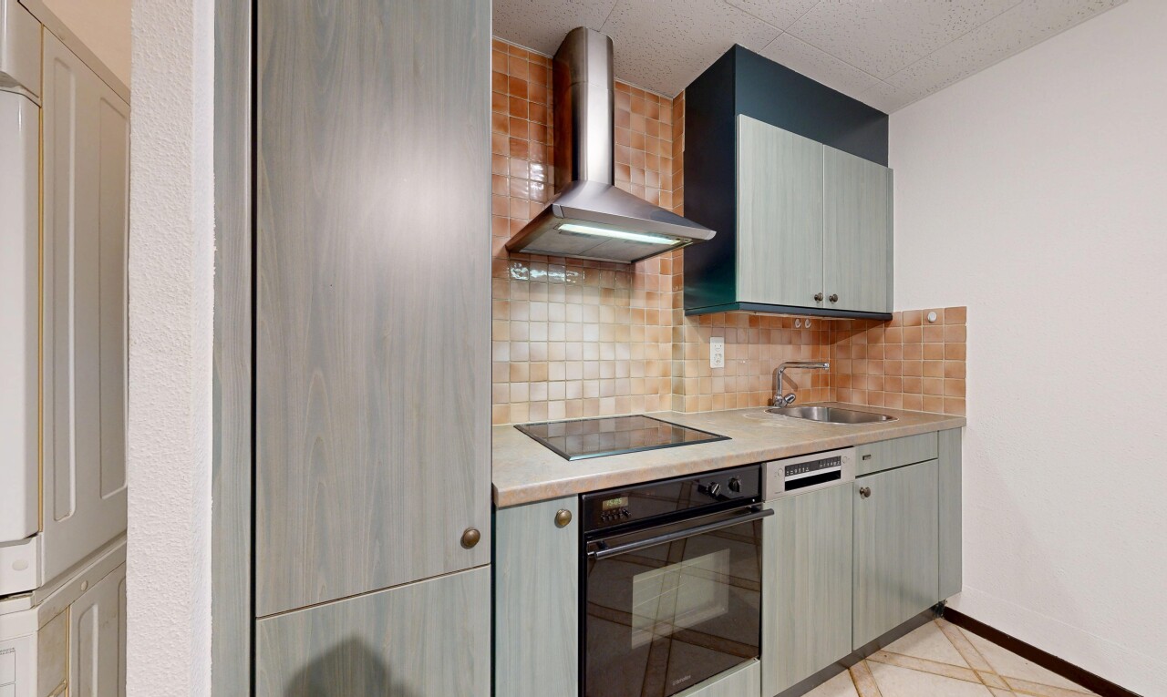cuisine avec hotte, four, light floor, plans de travail, et light countertops