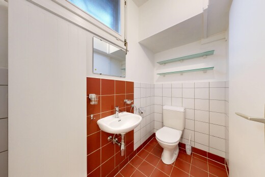 half bath featuring toilet and tile walls