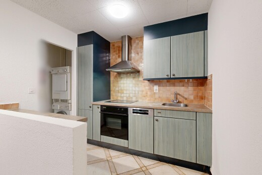 kitchen featuring black appliances, light countertops, stacked washer and dryer, decorative backsplash, and gray cabinetry