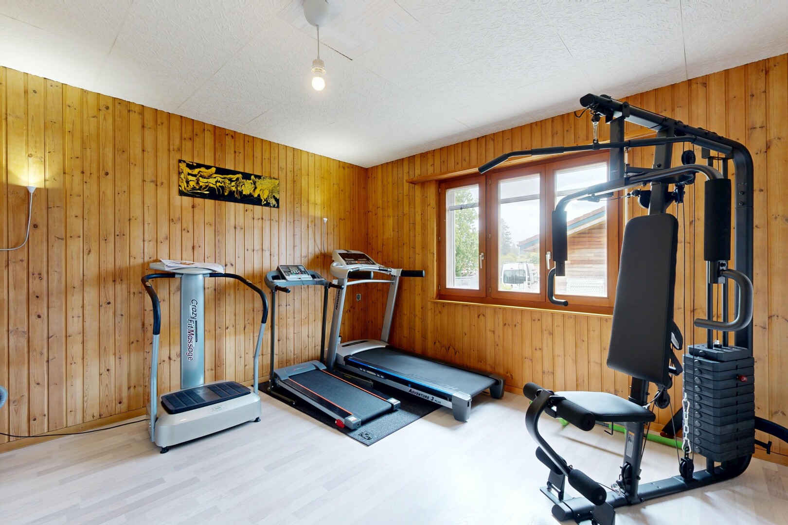 gym avec inside property, mur en bois, wood wall, sol en finition bois, et wood finish floor