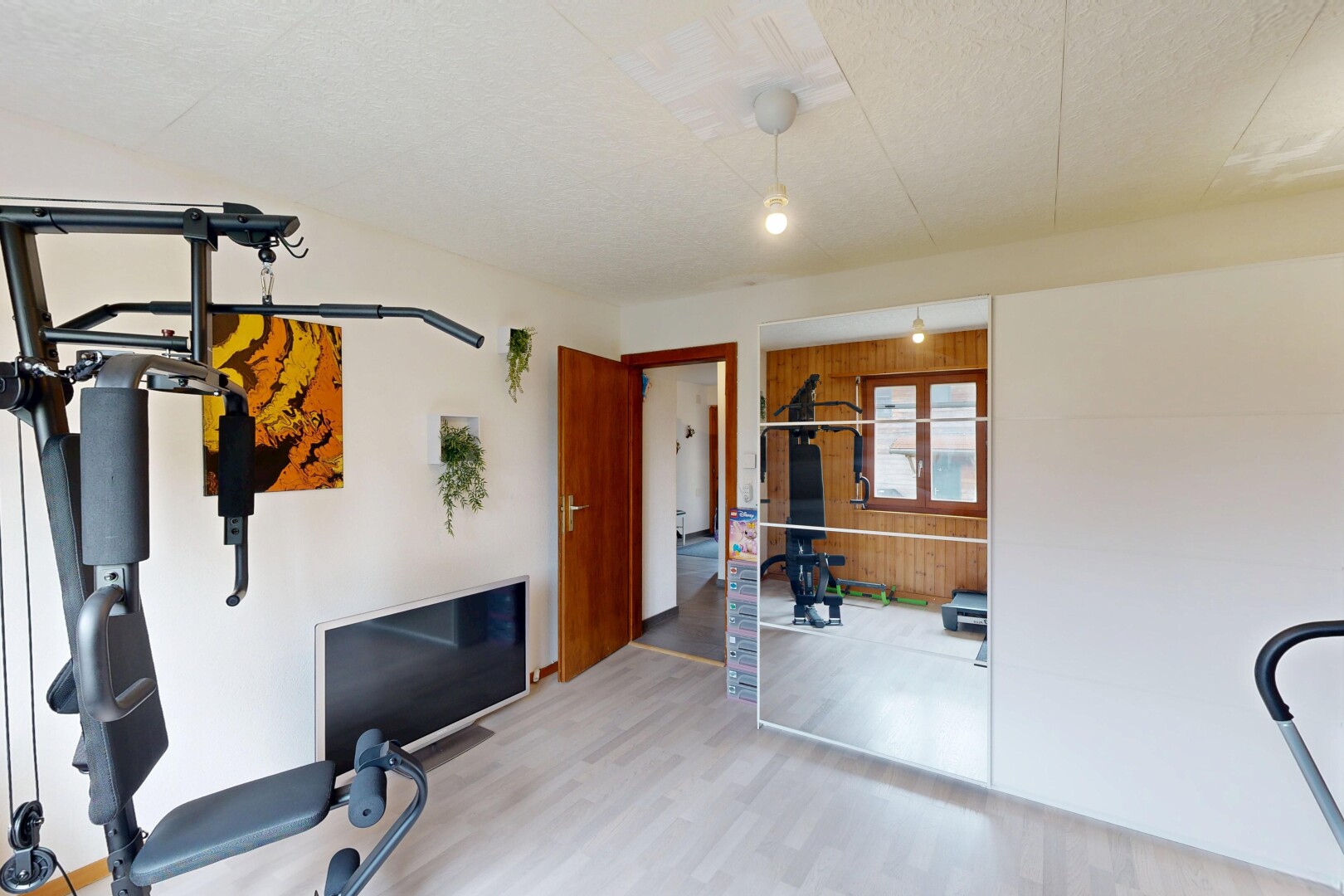 gym avec inside property, drywall, cloison sèche, wood finish floor, et sol en finition bois