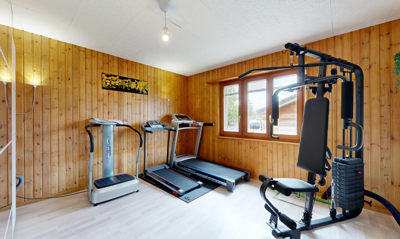 gym avec inside property, mur en bois, wood wall, sol en finition bois, et wood finish floor