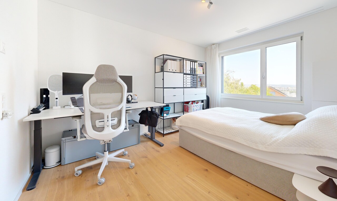 chambre avec espace bureau, cloison sèche, drywall, sol en finition bois, et wood finish floor