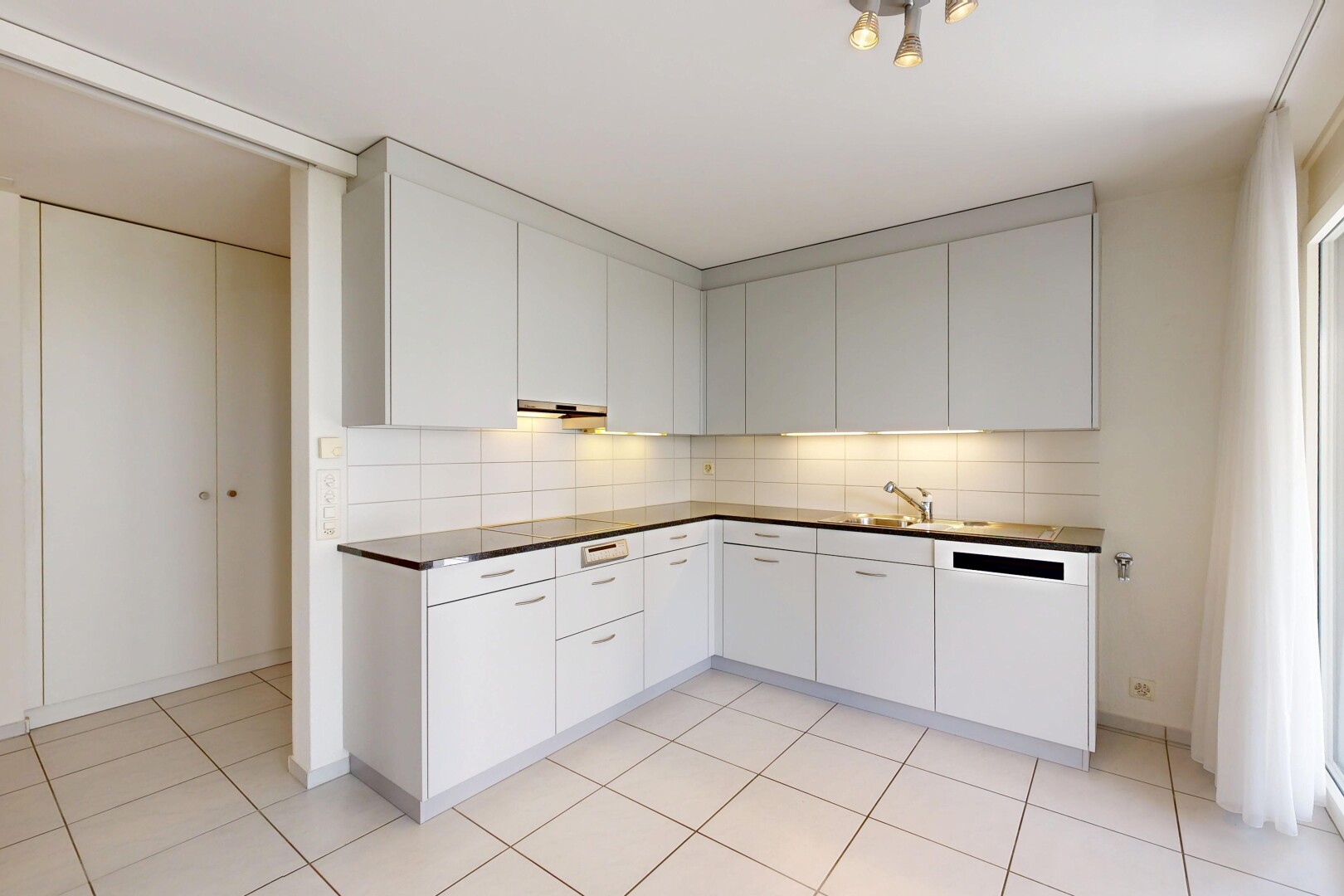 küche mit küchenrückwand beim herd, küchenrückwand beim Herd, light floor, dark countertops, und weiße schränke