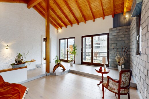 living area with wood-type flooring, a high wood beamed ceiling, and brick wall