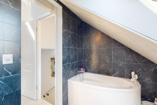 bathroom with tile walls, a bath, and lofted ceiling