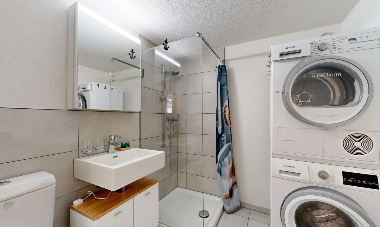 bathroom featuring a stall shower, stacked washer and clothes dryer, a textured ceiling, and light tile patterned floors