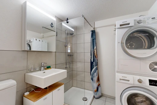 bathroom featuring a stall shower, stacked washer and clothes dryer, a textured ceiling, and light tile patterned floors
