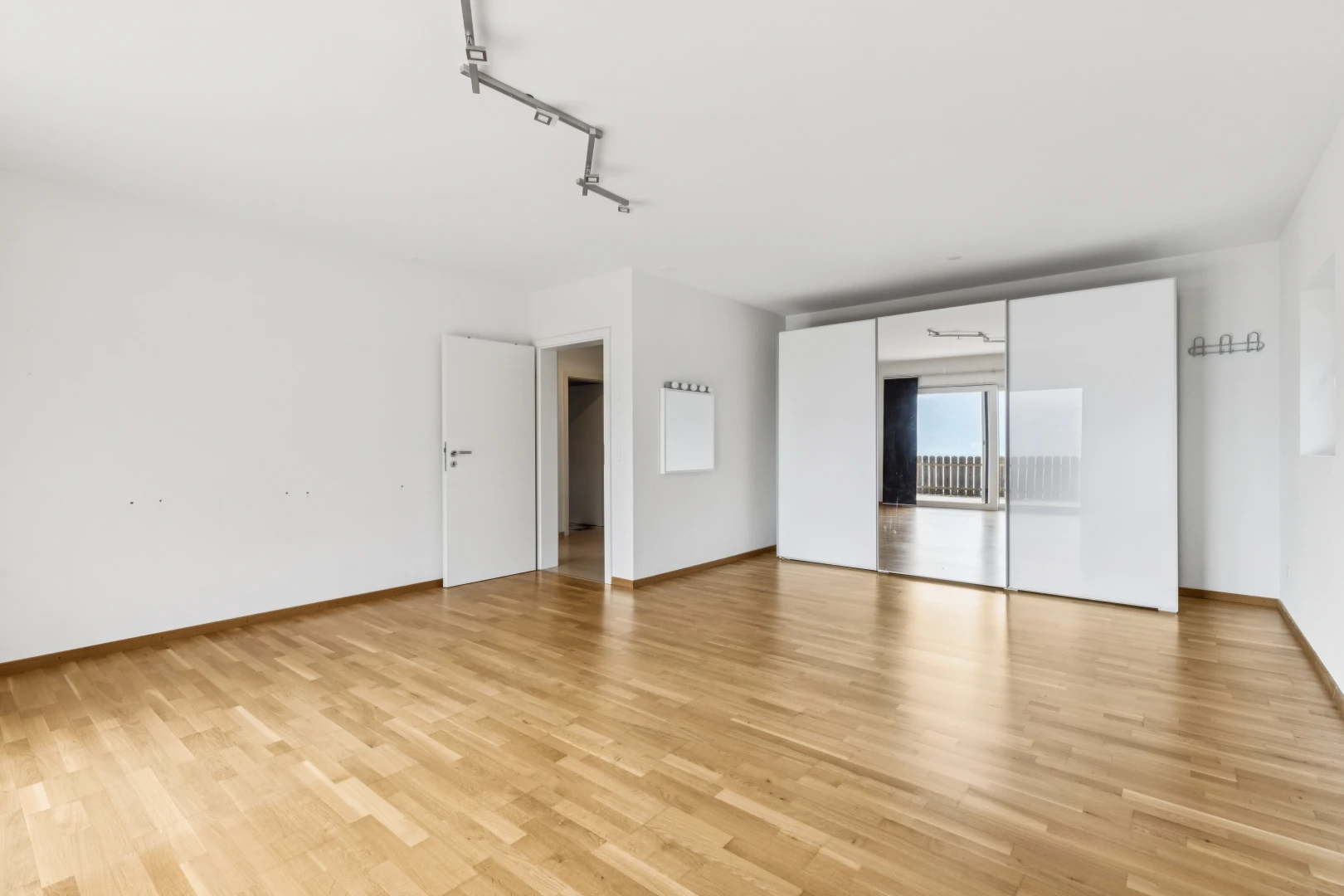 pièce vide avec éclairage sur rail, cloison sèche, drywall, sol en finition bois, et wood finish floor