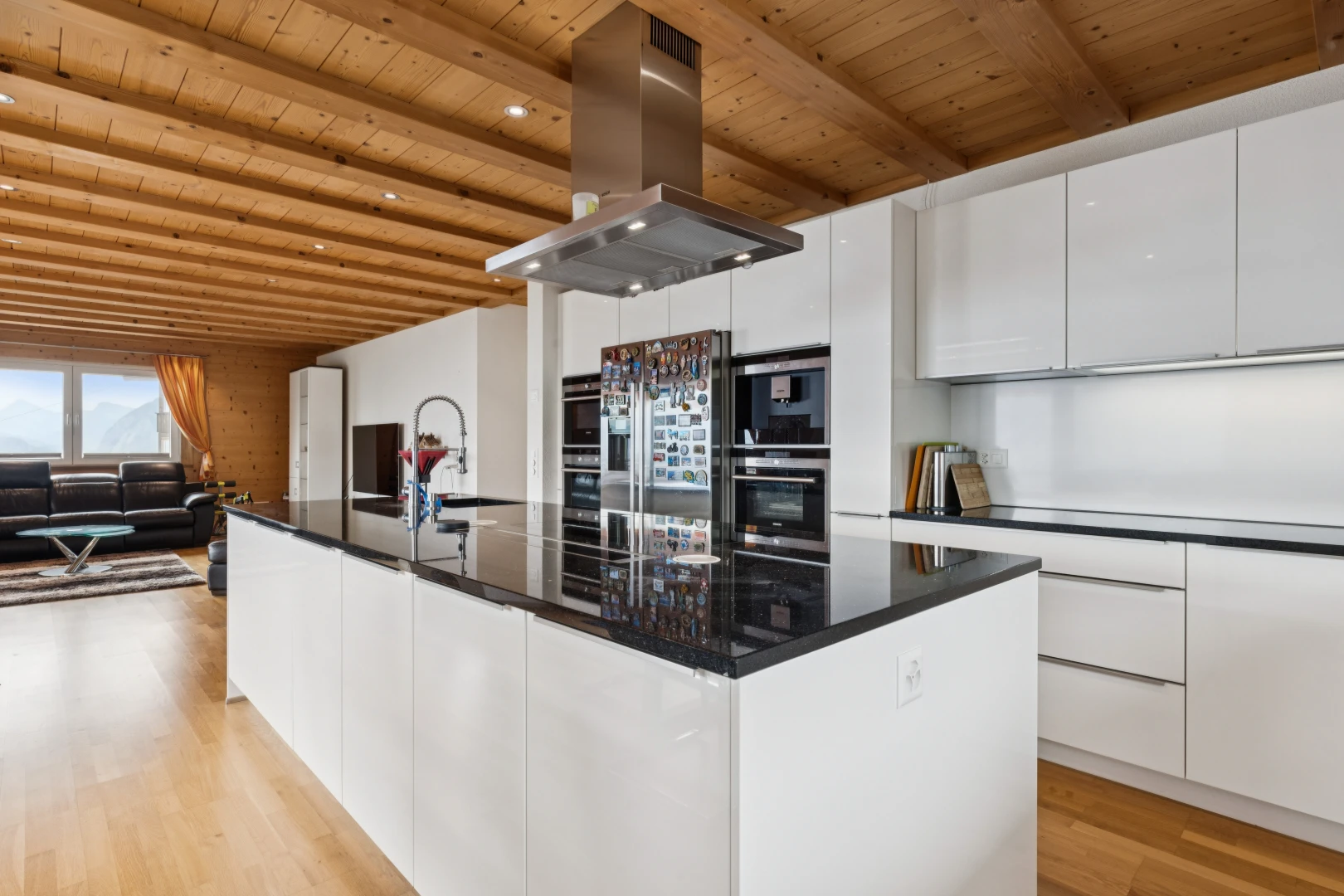 cuisine avec dark countertops, hotte, armoires à panneau plat, flat panel cabinets, et plafond en bois