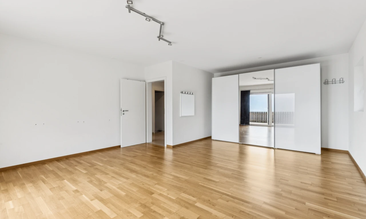pièce vide avec éclairage sur rail, cloison sèche, drywall, sol en finition bois, et wood finish floor