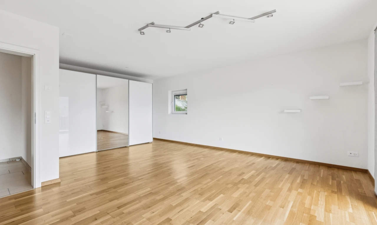 pièce vide avec cloison sèche, drywall, éclairage sur rail, sol en finition bois, et wood finish floor