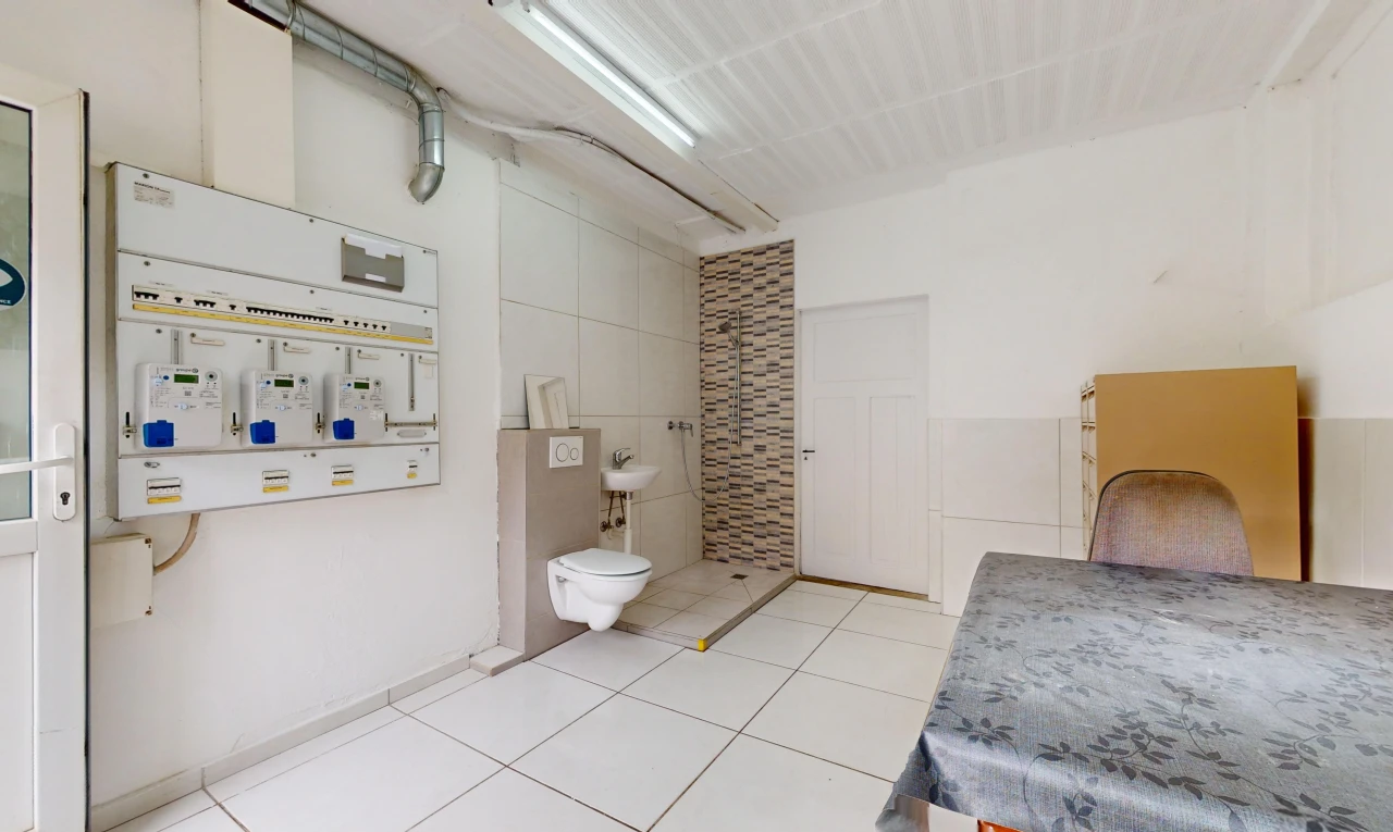 salle de bains avec carrelage, toilettes, mur carrelé, et chaudière